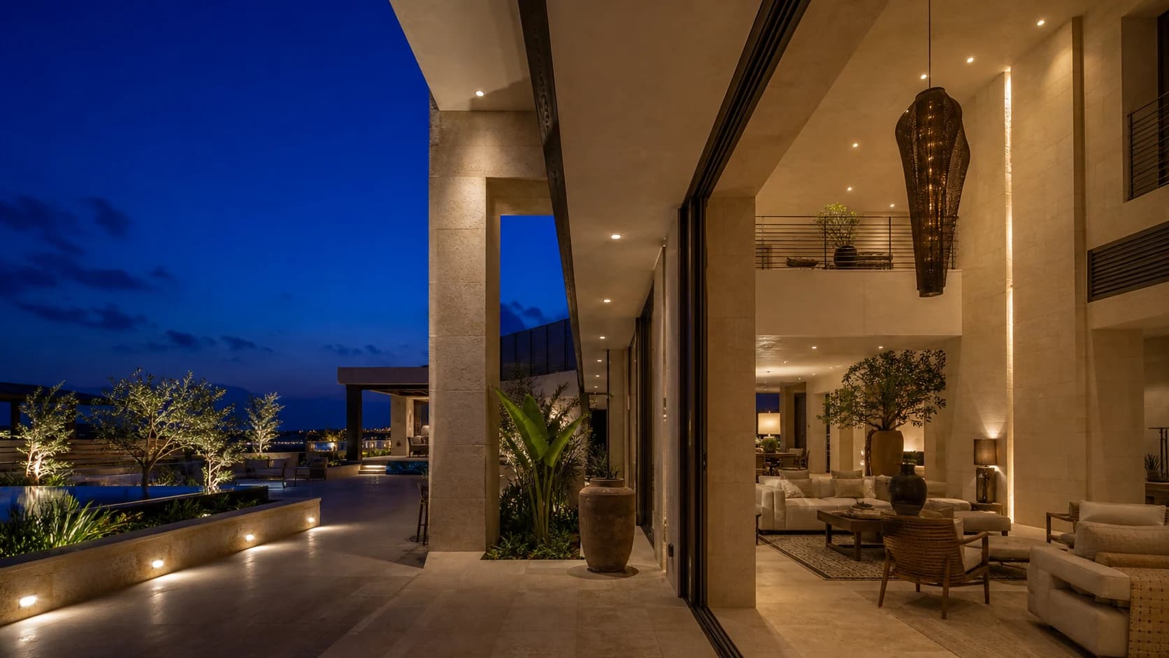 Contemporary villa at dusk with recessed indoor lights, a custom chandelier and landscaped outdoor lighting